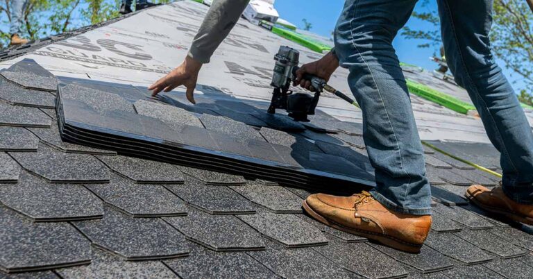 A roofer installing asphalt tiles