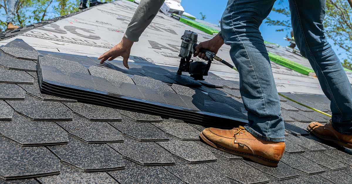 A roofer installing asphalt tiles